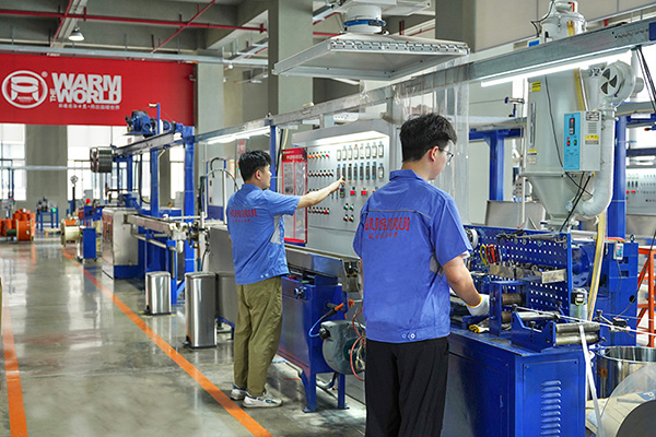 工人在操作電伴熱帶護(hù)套擠出設(shè)備。 環(huán)瑞電熱供圖